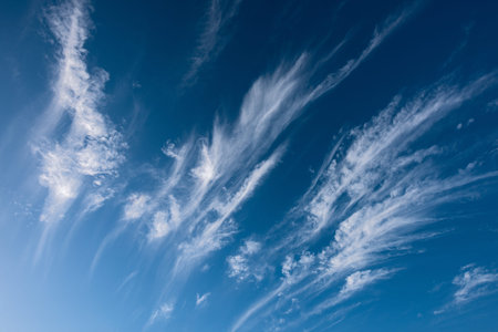 An abstract detail photograph of streaked white clouds against a deep blue sky in the heavens, taken...