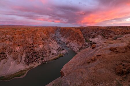 A beautiful pink sunset landscape view of the Augrabies Falls Gorge, mountains and river in South Africa, taken on a stormy cloudy golden evening.の写真素材