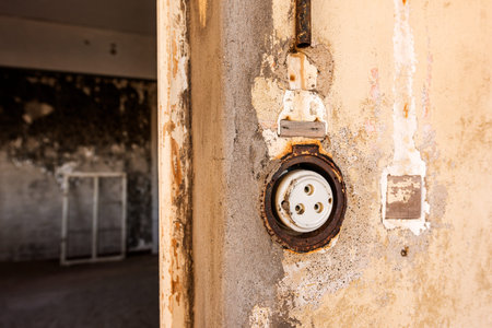 A close up photograph inside an abandoned house of an old electrical socket on a wall, taken in the...