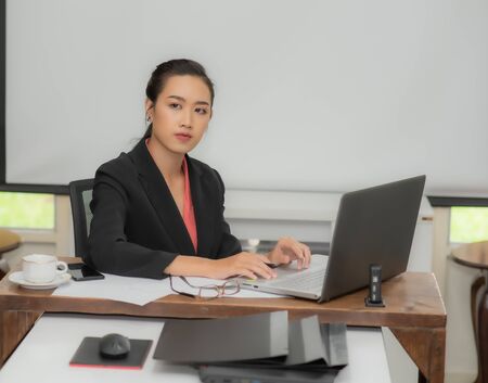 Young pretty business woman with notebook in the bright modern office indoors.の写真素材