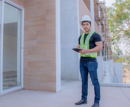 The foreman wearing a white helmet stood on a tablet in the construction site.の写真素材