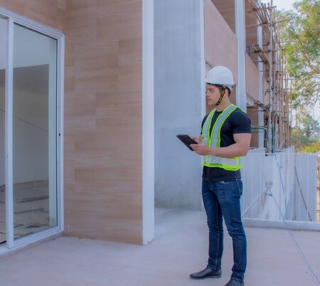 The foreman wearing a white helmet stood on a tablet in the construction site.の写真素材