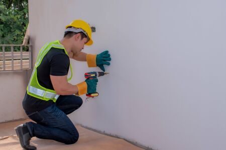 Strong male workers penetrate the wall, work hard for menの写真素材