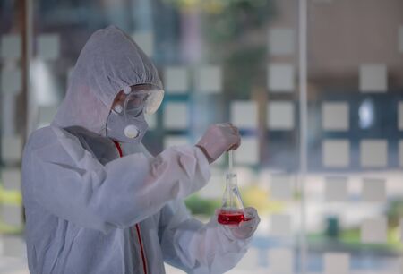 Male scientist testing experiment in a science lab where he holding scientific test tube full of chemical substance. The researcher is analyzing medicine related innovation. Microbiology concept.の写真素材