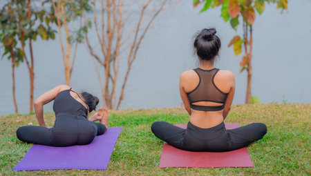 Rear view of attractive Asian girls in sportswear, sitting in lotus positions while doing yoga.