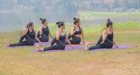 Group of young females practicing yoga the lakeside during the sunrise.の写真素材