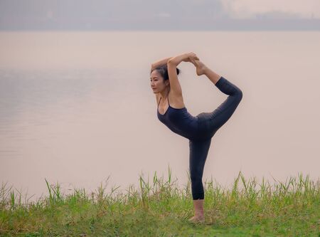 Strong women practice difficult yoga postures by the lake.の写真素材