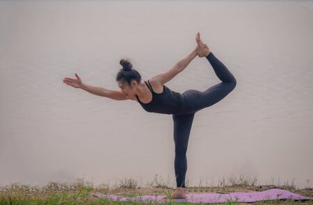 Strong women practice difficult yoga postures by the lake.の写真素材