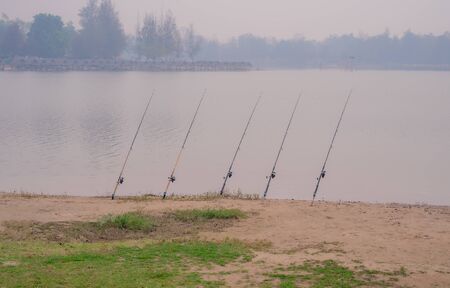 Fisherman fishing with a fishing rod. Silhouette. Trees and cottages in the background reservoirの写真素材
