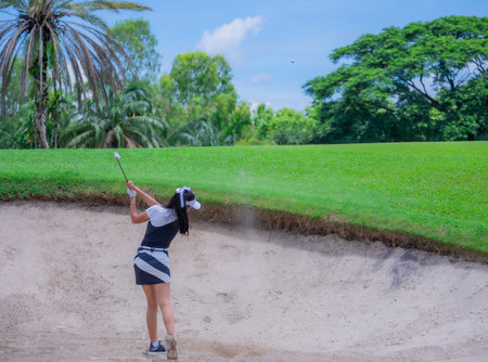 Thai young woman golf player in action swing in sand pit during practice before golf tournament at golf courseの写真素材