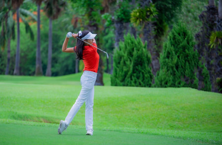 Woman golf player in action being setup address of back swing to hit the golf ball away from T-OFF to the destination on the green, fairway at day light sky.の写真素材