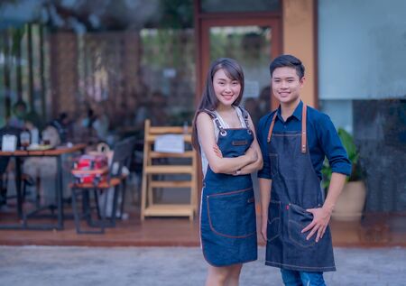 Portrait of male and female coffee shop owner standing in the storefrontの写真素材