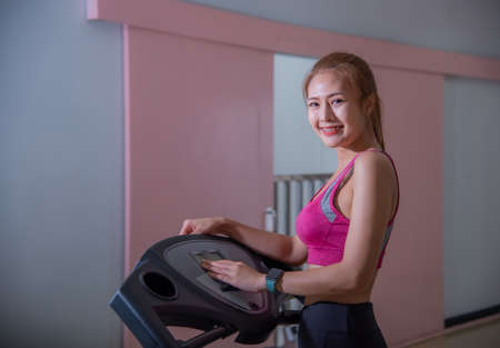 Full length profile shot of a young woman running on a treadmill in the gym.の写真素材