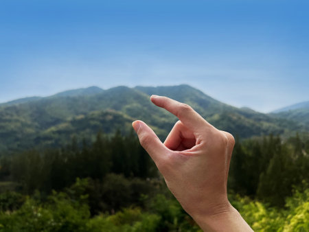 Human hand pointing with finger on mountain background. Focus on hand.の写真素材