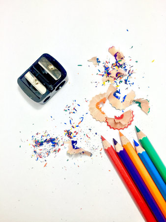 Color pencils with sharpener and shaves on white paper