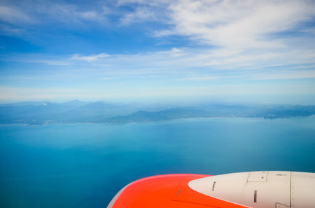 wing of airplane with sea and land from above