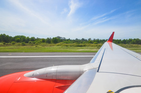 wing of airplane with runway view and blue sky from the window.
