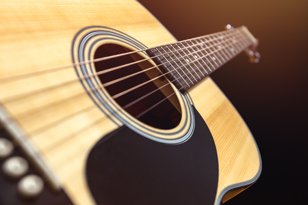 Yellow acoustic wooden guitar on a black backgroundの写真素材