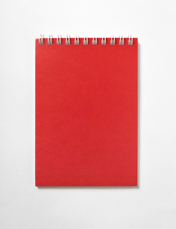 Red open Notepad with spiral binding, top view, white backgroundの写真素材