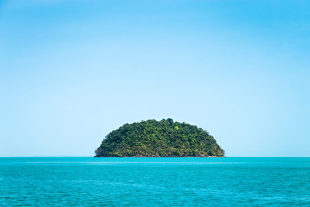 Round green island. Seascape with tropical island, Thailand. Blue clear sky.