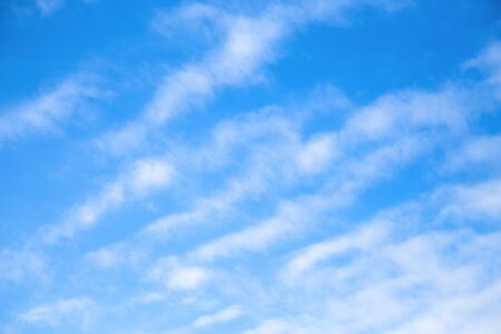Cloudscape Blue sky background with white clear clouds. The texture of the sky with translucent light feathery clouds. Diagonal direction.の写真素材
