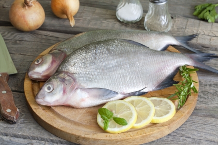 Bream raw fish on cutting board in the kitchen with spicesの写真素材