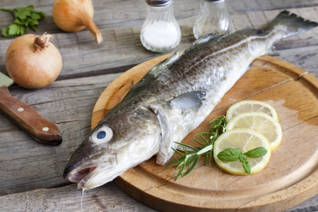 Cod raw fish on cutting board in the kitchen with spicesの写真素材