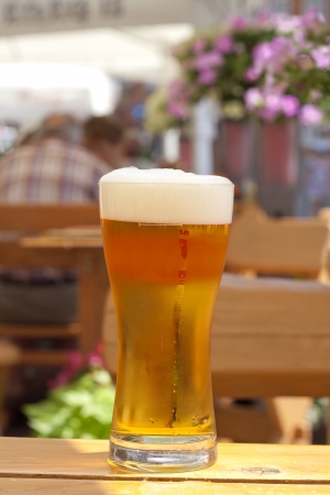Glass of beer in restaurant on the table outdoor in the sunの写真素材