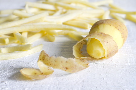 Potatoes with peel and chips on white boardの写真素材