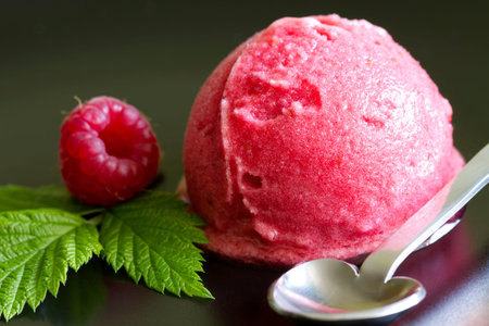 Scoop of raspberry ice cream with fresh fruit and green leafの写真素材