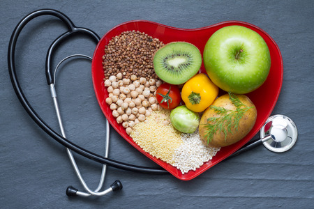 Healthy food on red heart plate cholesterol diet concept