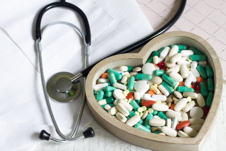 Stethoscope and pills in heart against cardiogram medical concept