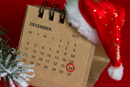 Calendar and circled christmas date on red background with santa claus hatの写真素材