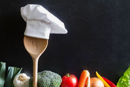 Chef's hat on spoon and vegetables cooking foodの写真素材