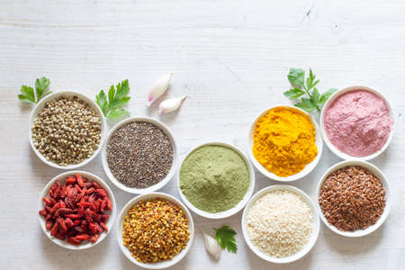 Various superfoods in small bowls on white wooden background. Healthy food conceptの写真素材