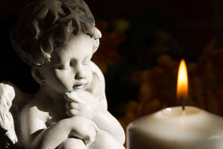 Angel and burning candle on dark backgroundの写真素材