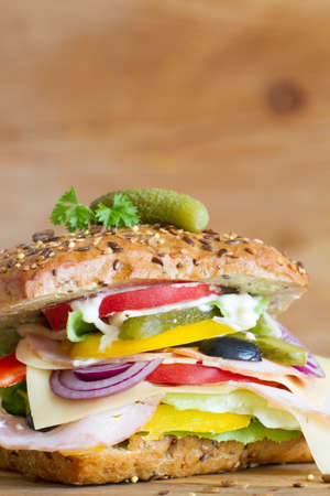 Appetizing sandwich with cured meat, cheese and vegetables on wooden backgroundの写真素材