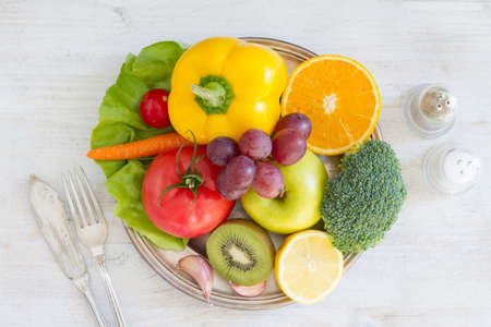 Plate full of fruits and vegetables, cutlery, spices. Healthy meal conceptの写真素材
