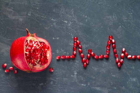 Fruit pomegranate and ECG cardiogram from pomegranate seeds, healthy heart diet concept abstractの写真素材