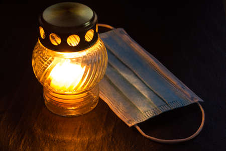 Burning candle and mask on black background. Epidemic coronavirus victims memory conceptの写真素材