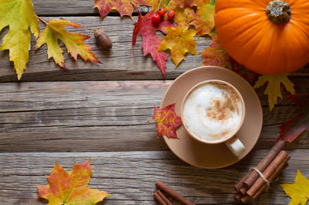 Autumn composition - cappuccino, autumn leaves and pumpkin on wooden backgroundの写真素材
