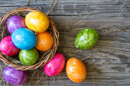 Colorful easter eggs in basket on old wooden boards backgroundの写真素材