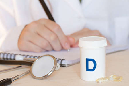 Vitamin D in capsules, stethoscope and doctor in background, health and immunity conceptの写真素材