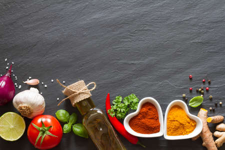 Cooking background. Vegetables, herbs and spices on black slateの写真素材