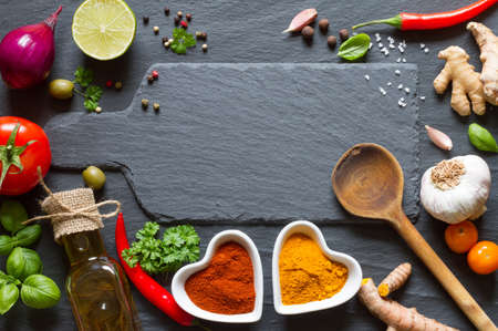 Cooking background. Vegetables, herbs and spices on black slateの写真素材