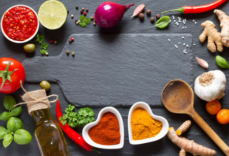 Cooking background. Vegetables, herbs and spices on black slateの写真素材