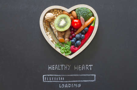Healthy food in heart and progress bar loading with message "healthy heart" on blackboard, diet conceptの写真素材