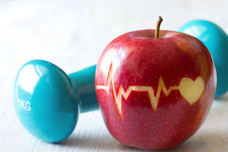 Heartbeat line on red apple and dumbbell, healthy heart diet and sport conceptの写真素材