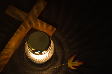 Burning candle with cross on dark background, All Saints Day concept