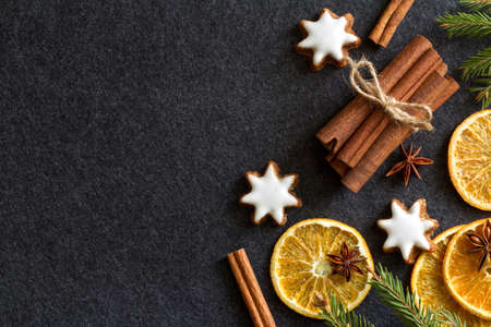 Christmas dark background with dried orange, cinnamon and cookiesの写真素材